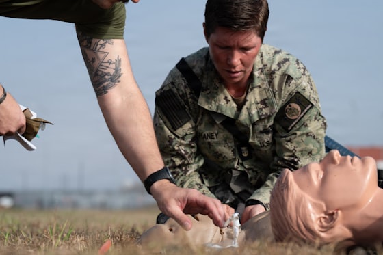 Instructor and uniformed trainee practicing airway skills on a training manikin outdoors