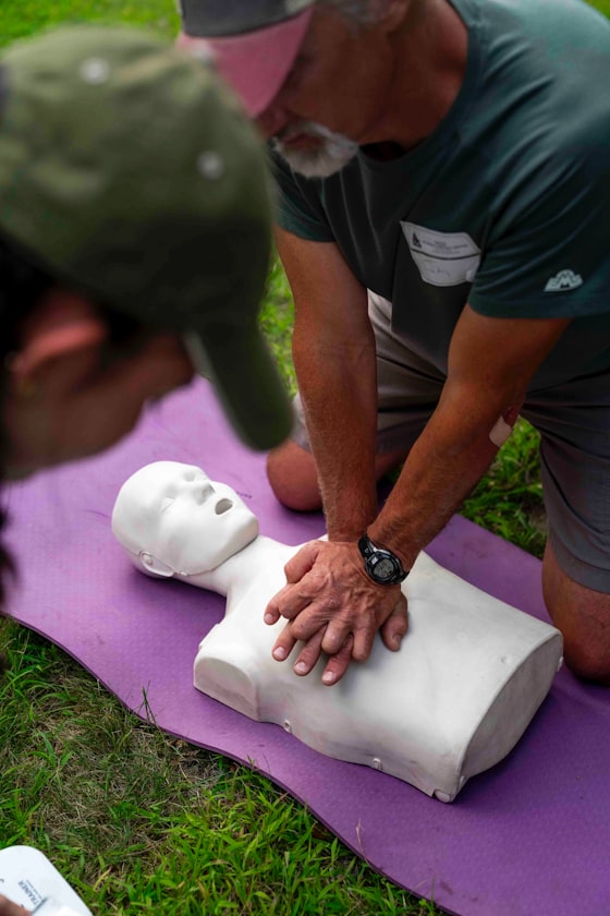 CPR instructor demonstrating chest compressions on a training manikin outdoors